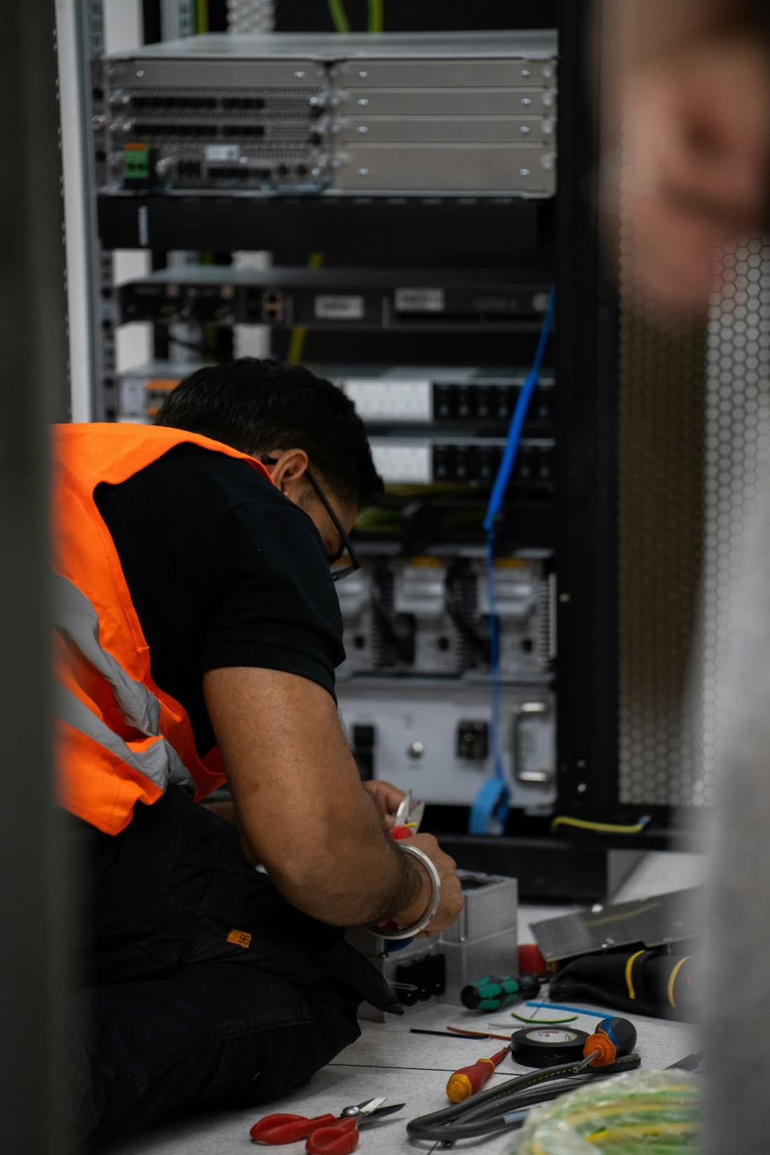 Engineer in hi-vis terminating services inside a site power and communications cabinet