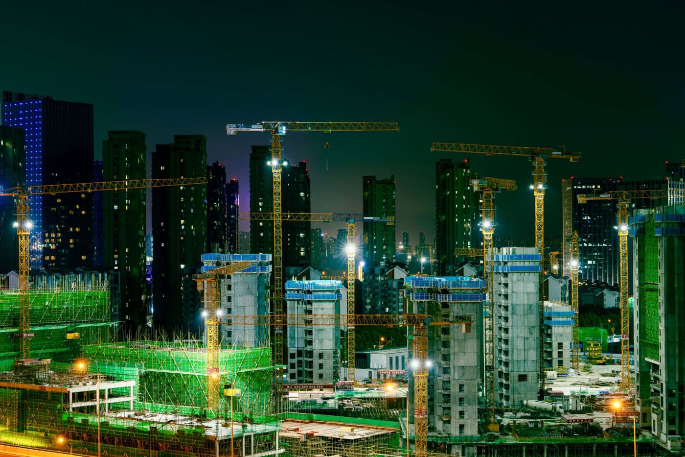 Major construction site operating at night under tower cranes and floodlights
